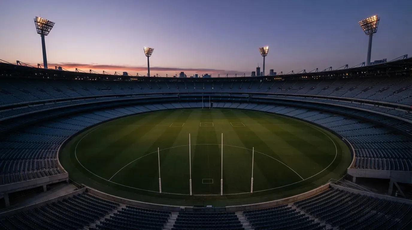 An empty football stadium with floodlight masts at dusk