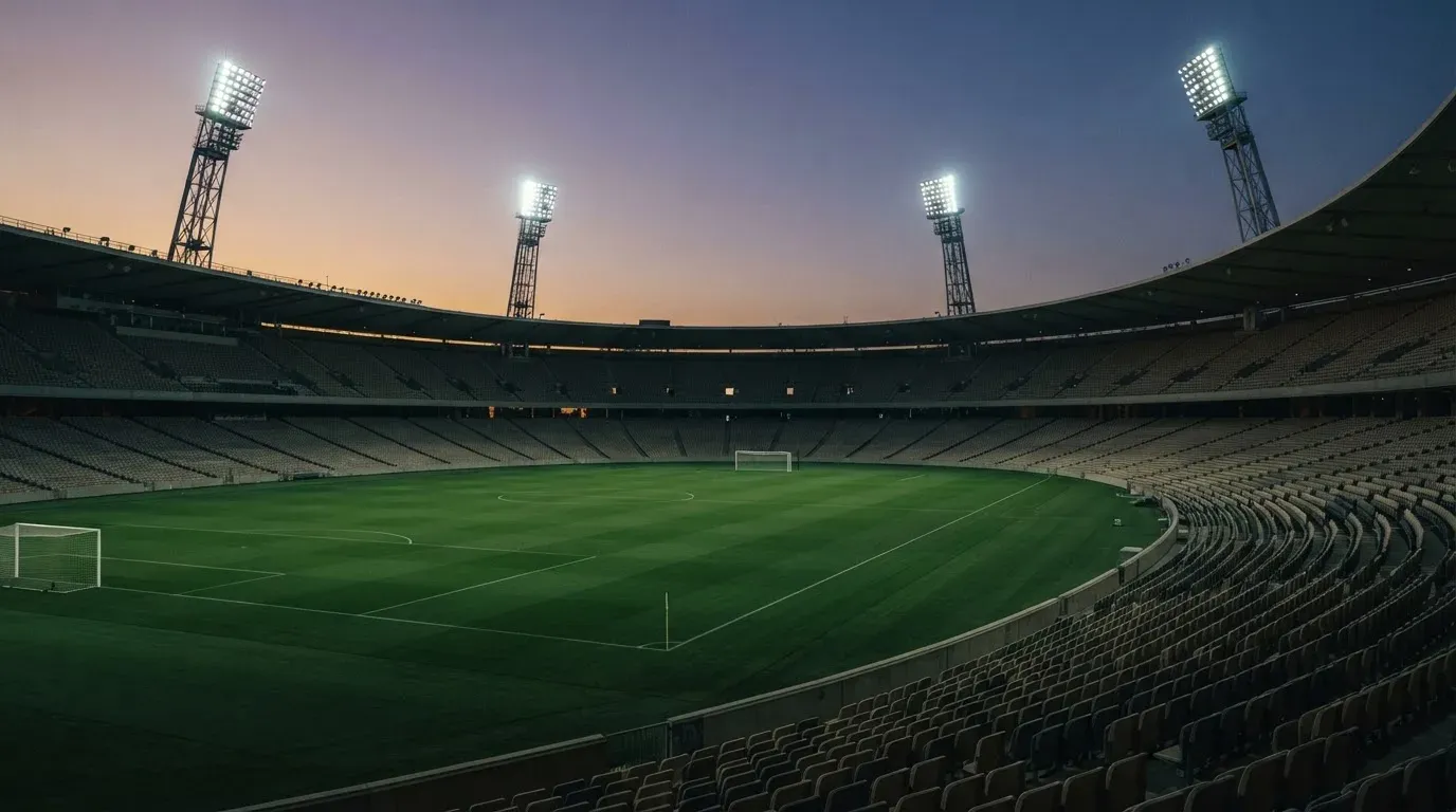 An empty football stadium with floodlight masts at dusk