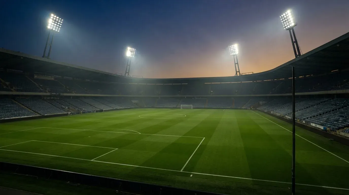 An empty football stadium with floodlight masts at dusk