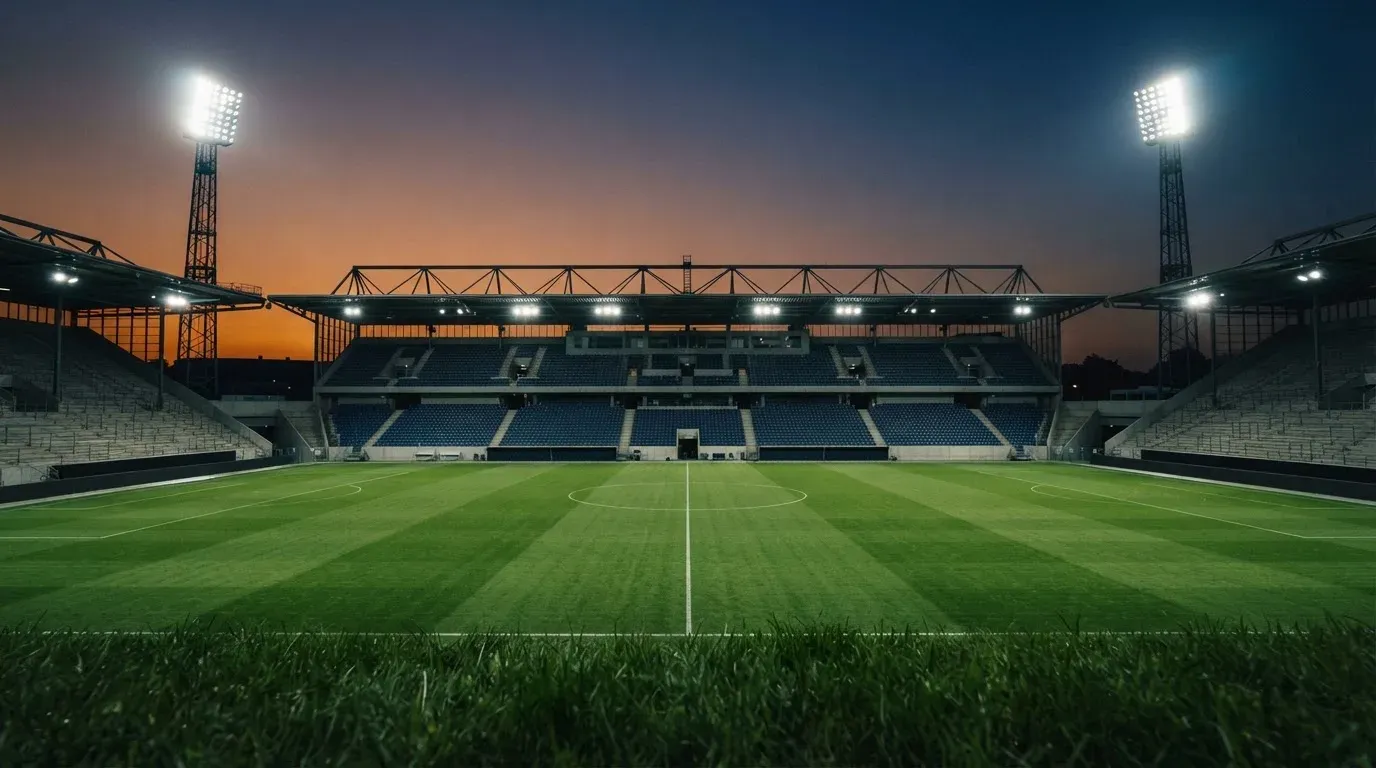 An empty football stadium with floodlight masts at dusk