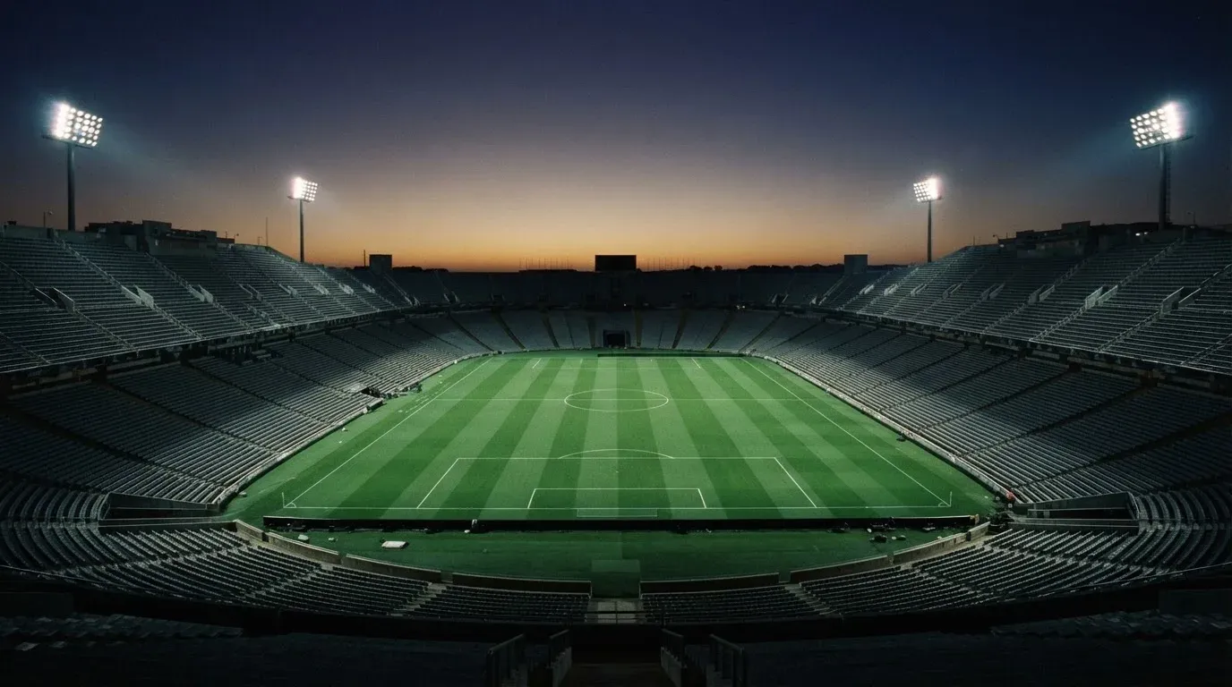 An empty football stadium with floodlight masts at dusk