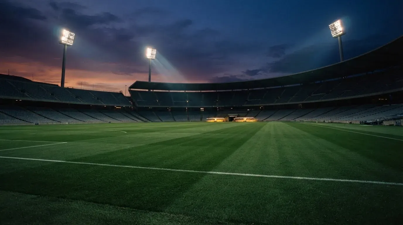 An empty football stadium with floodlight masts at dusk