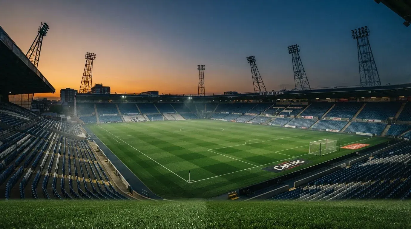 An empty football stadium with floodlight masts at dusk