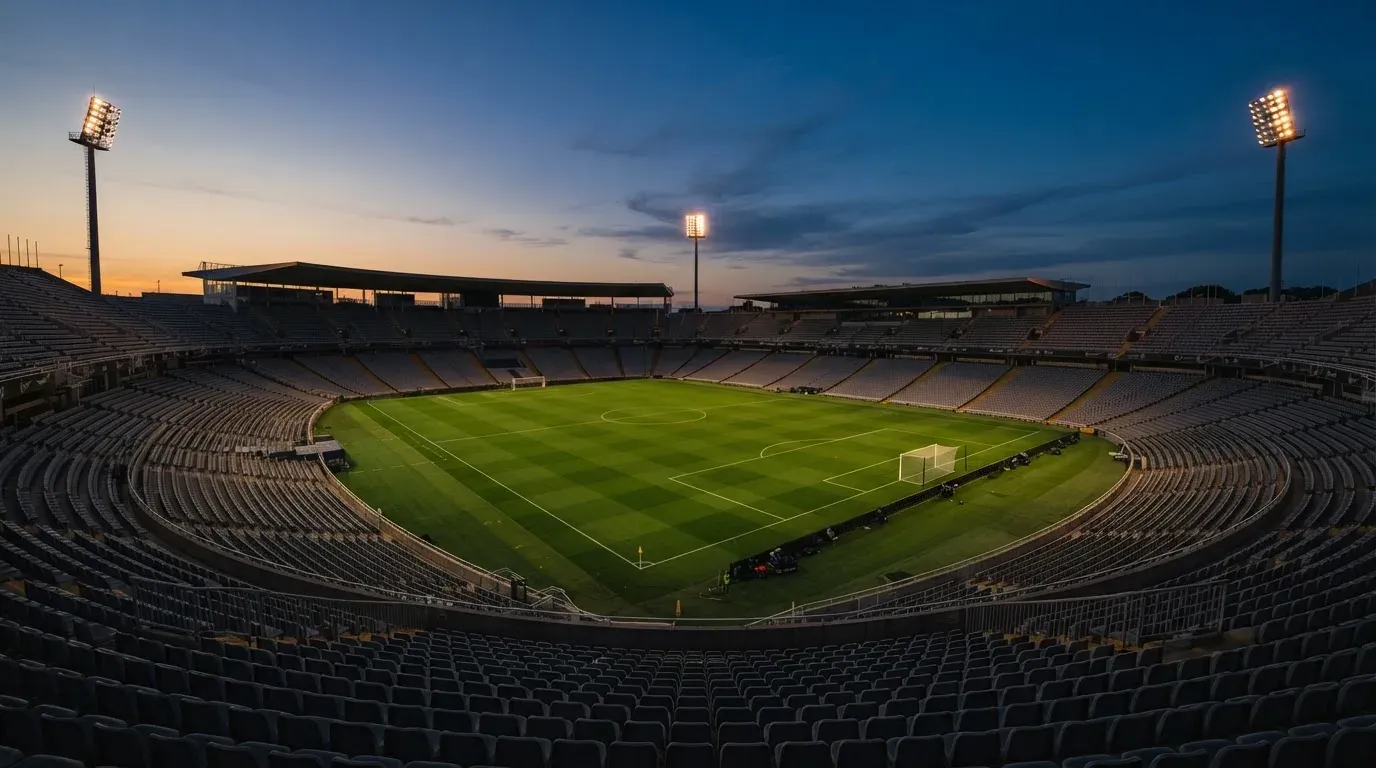 An empty football stadium with floodlight masts at dusk