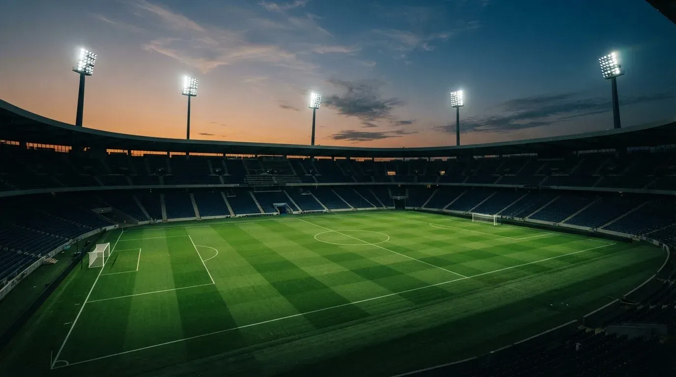 An empty football stadium with floodlight masts at dusk