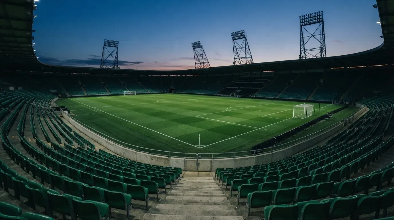 An empty football stadium with floodlight masts at dusk