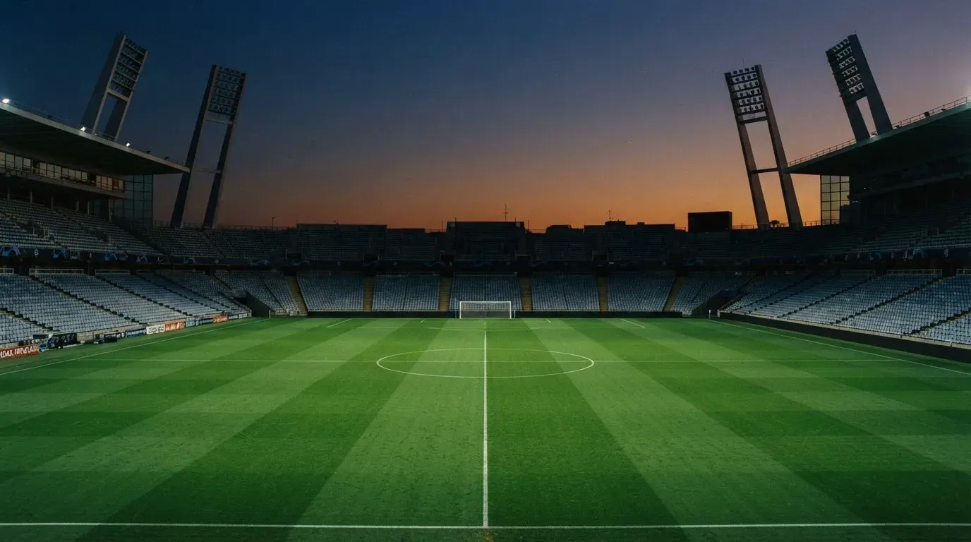 An empty football stadium with floodlight masts at dusk