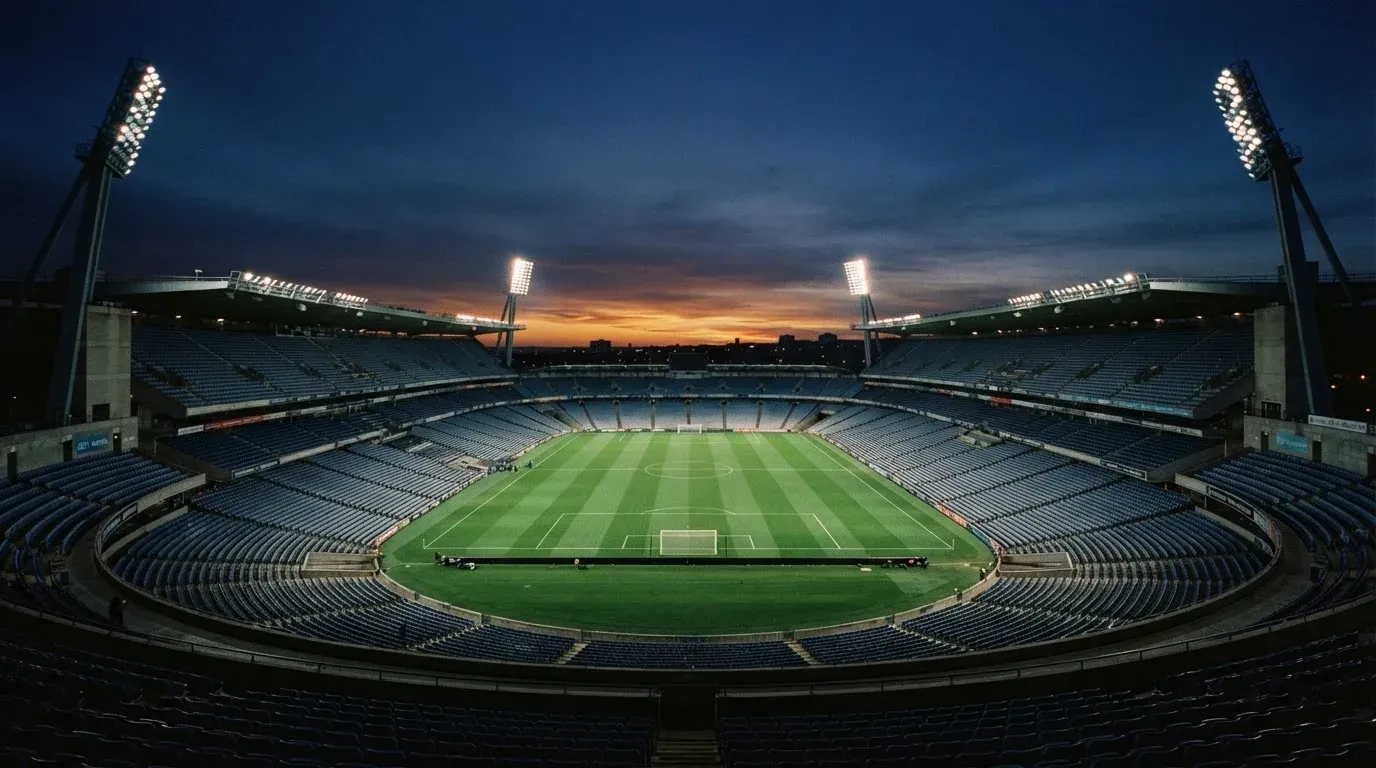 An empty football stadium with floodlight masts at dusk