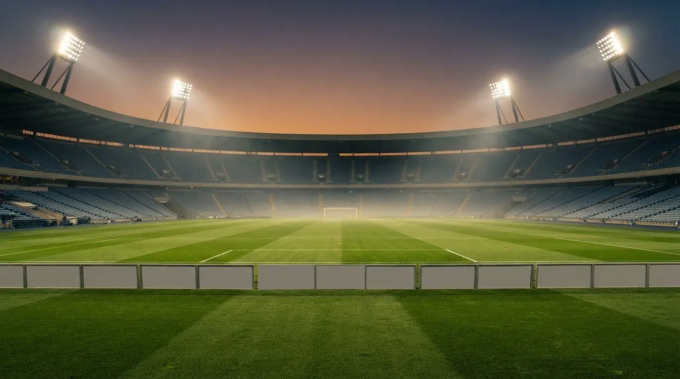 An empty football stadium with floodlight masts at dusk