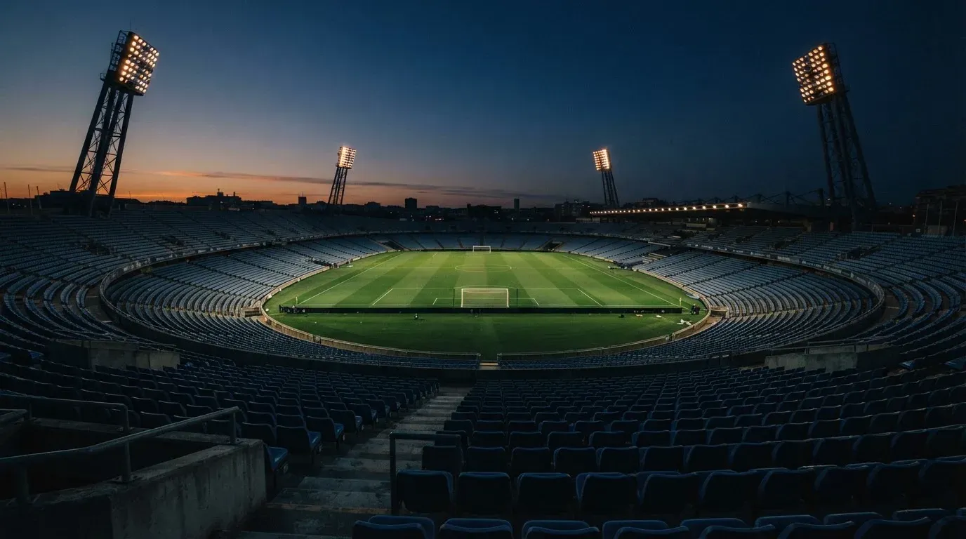 An empty football stadium with floodlight masts at dusk
