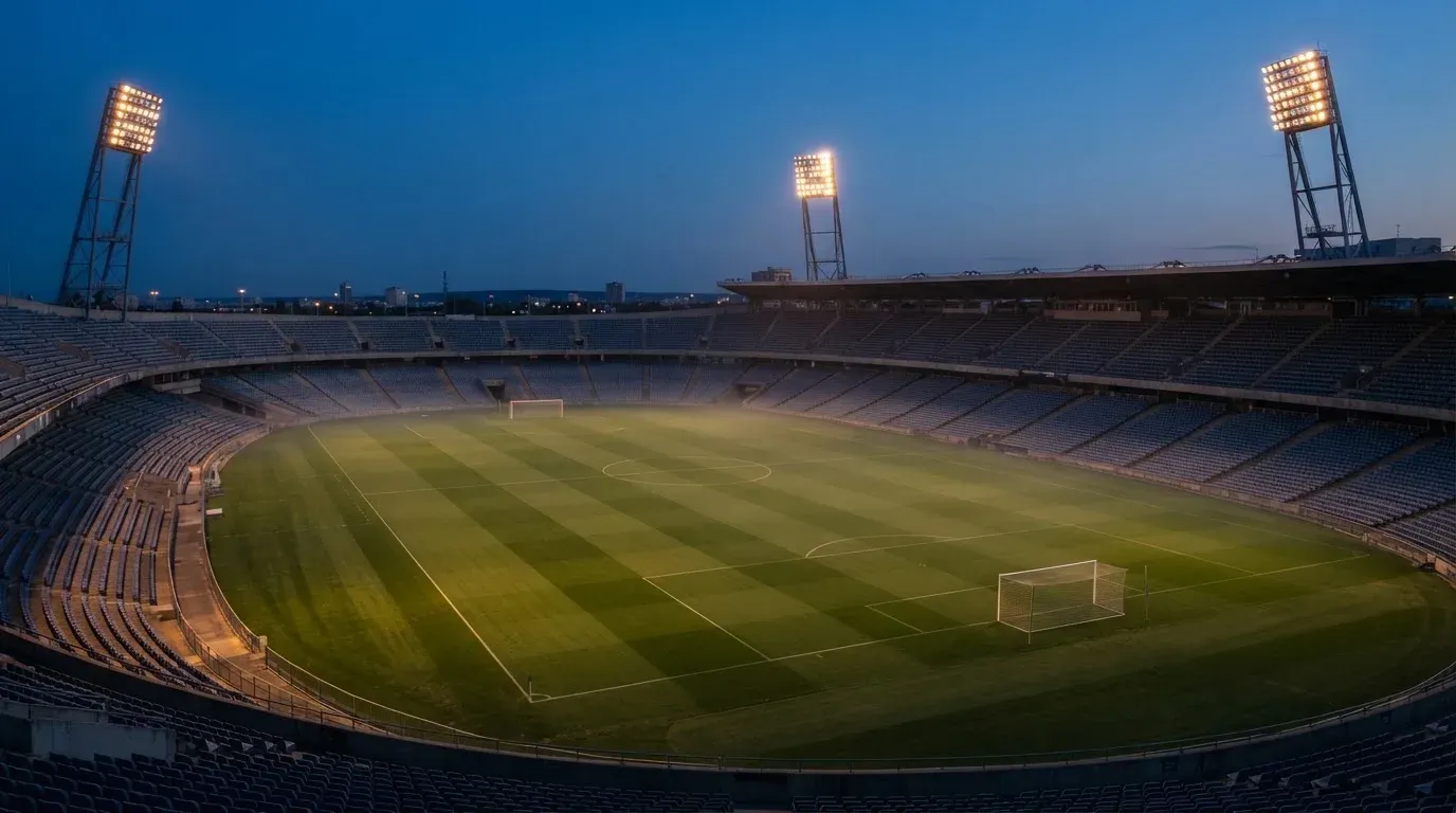 An empty football stadium with floodlight masts at dusk