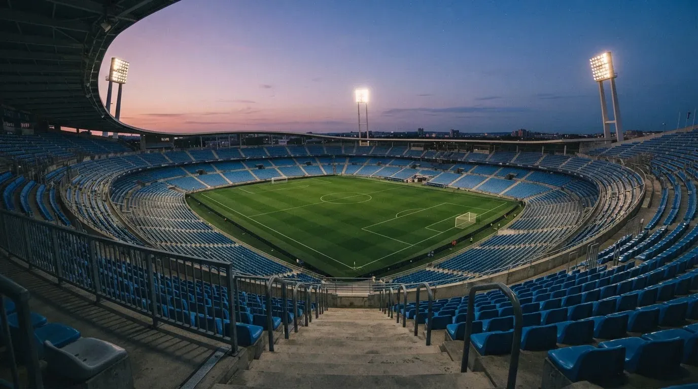 An empty football stadium with floodlight masts at dusk