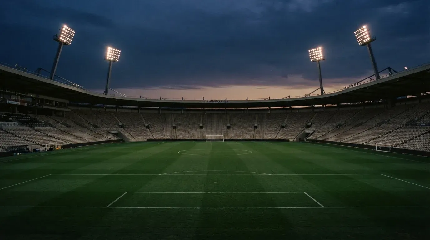 An empty football stadium with floodlight masts at dusk