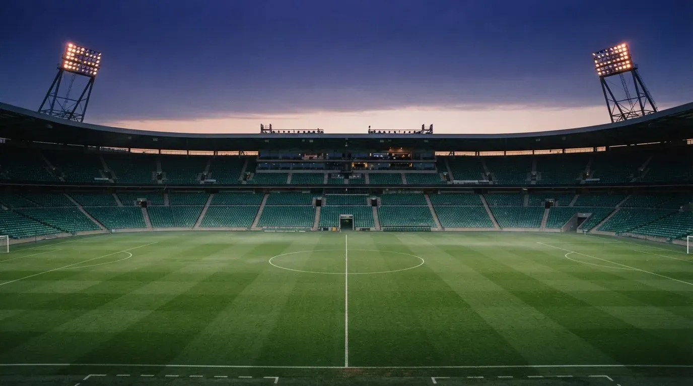 An empty football stadium with floodlight masts at dusk