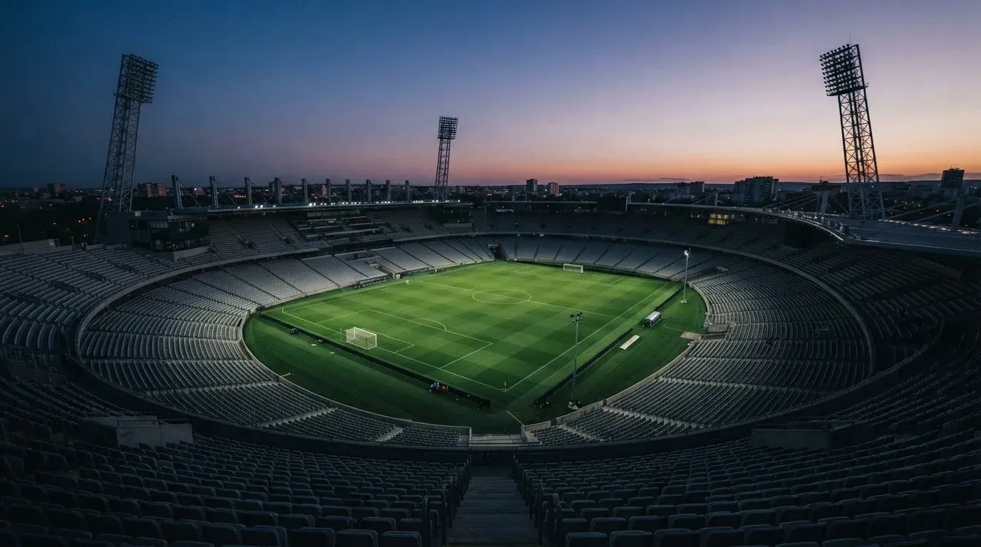 An empty football stadium with floodlight masts at dusk