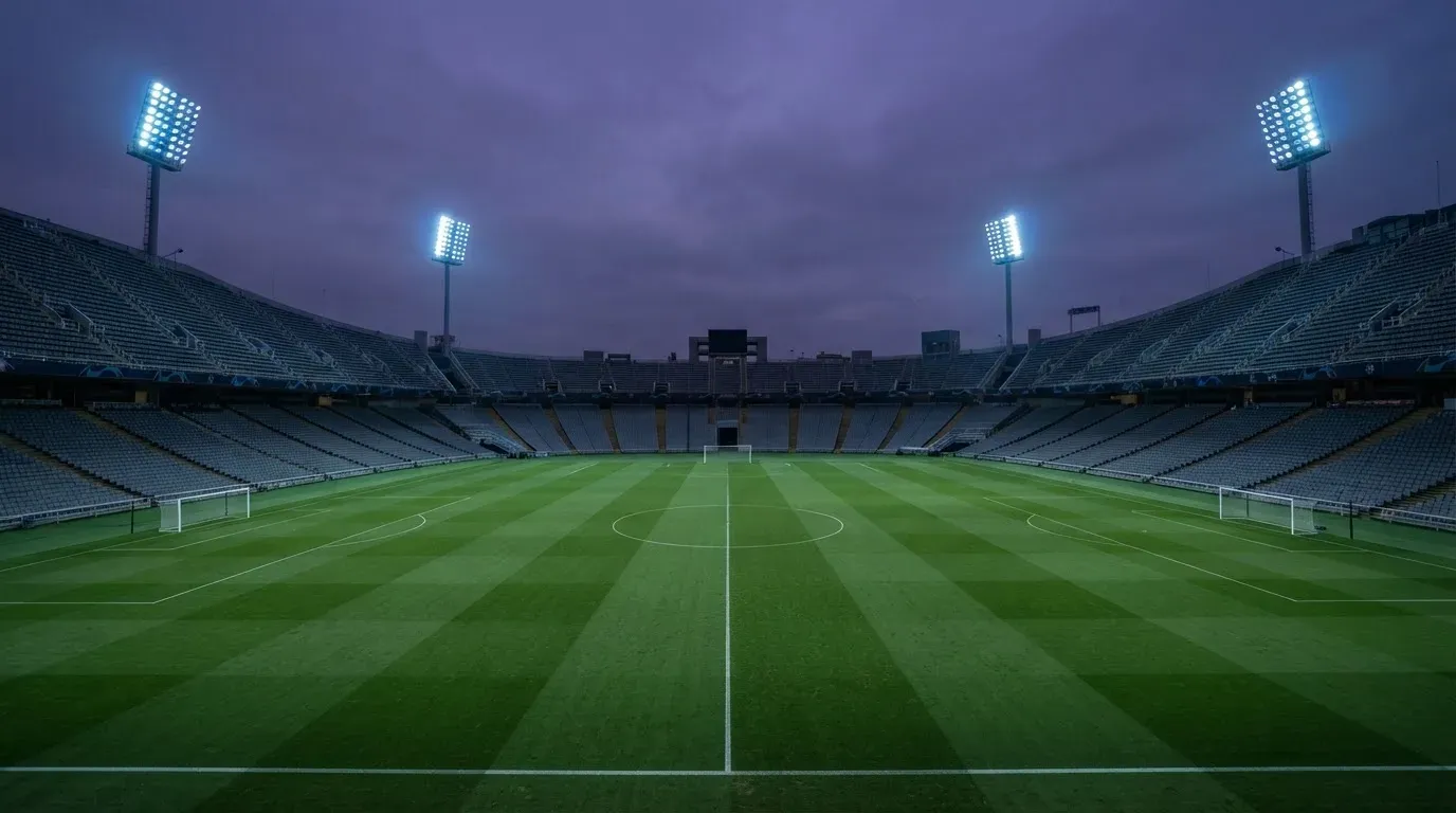 An empty football stadium with floodlight masts at dusk