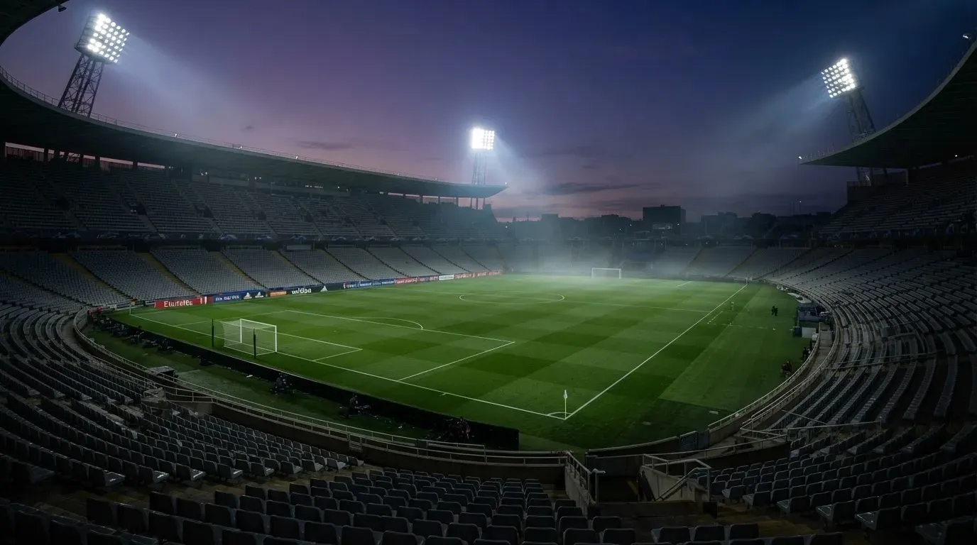 An empty football stadium with floodlight masts at dusk
