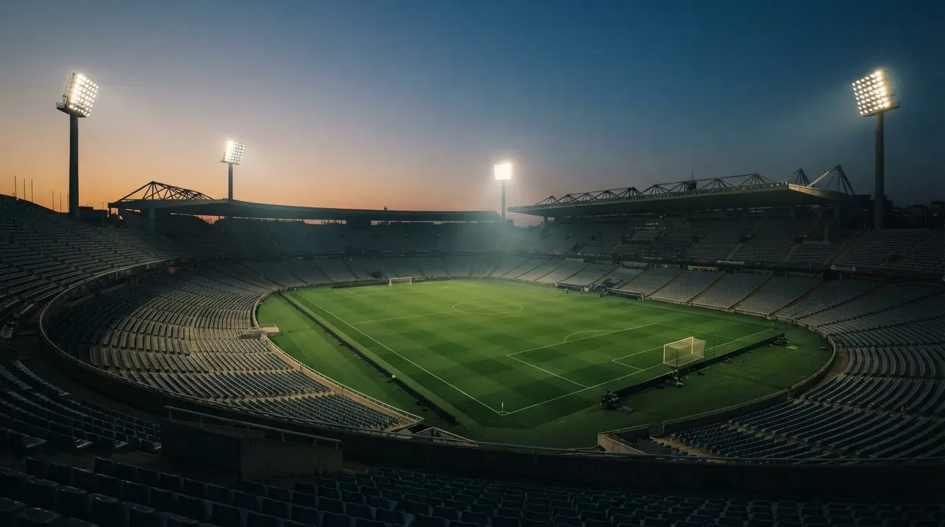 An empty football stadium with floodlight masts at dusk