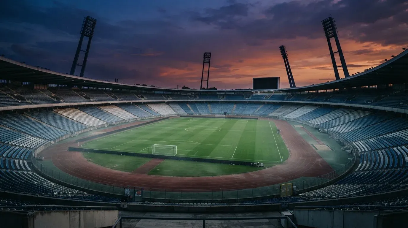 An empty football stadium with floodlight masts at dusk