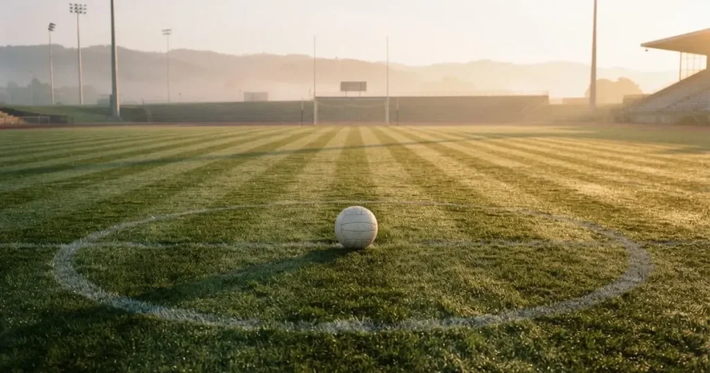 A ball on the centre spot of a grass pitch in morning light