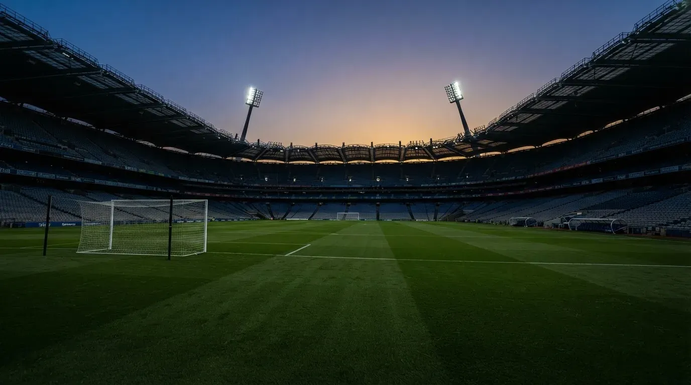 An empty football stadium with floodlight masts at dusk
