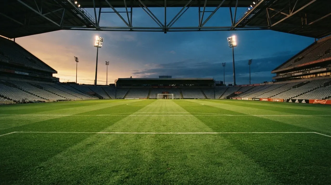 An empty football stadium with floodlight masts at dusk