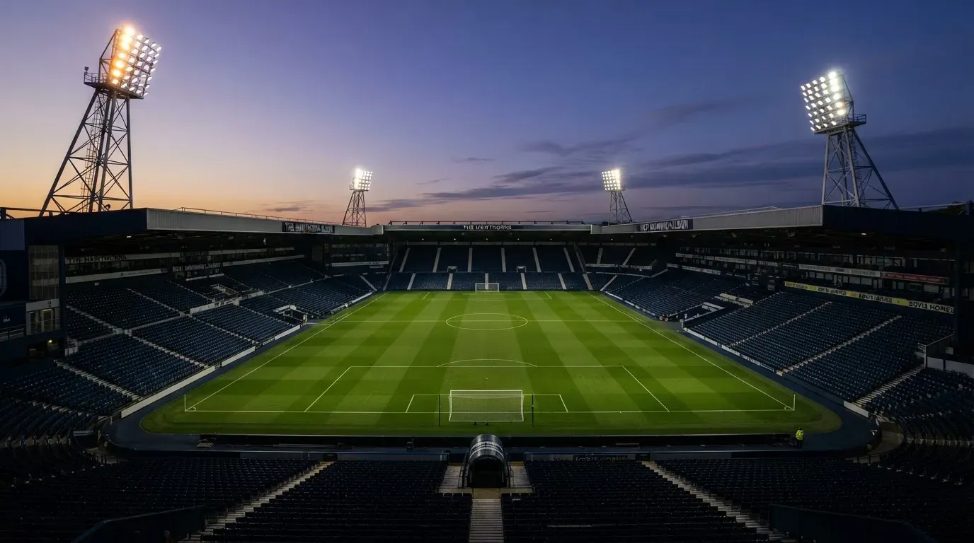 An empty football stadium with floodlight masts at dusk
