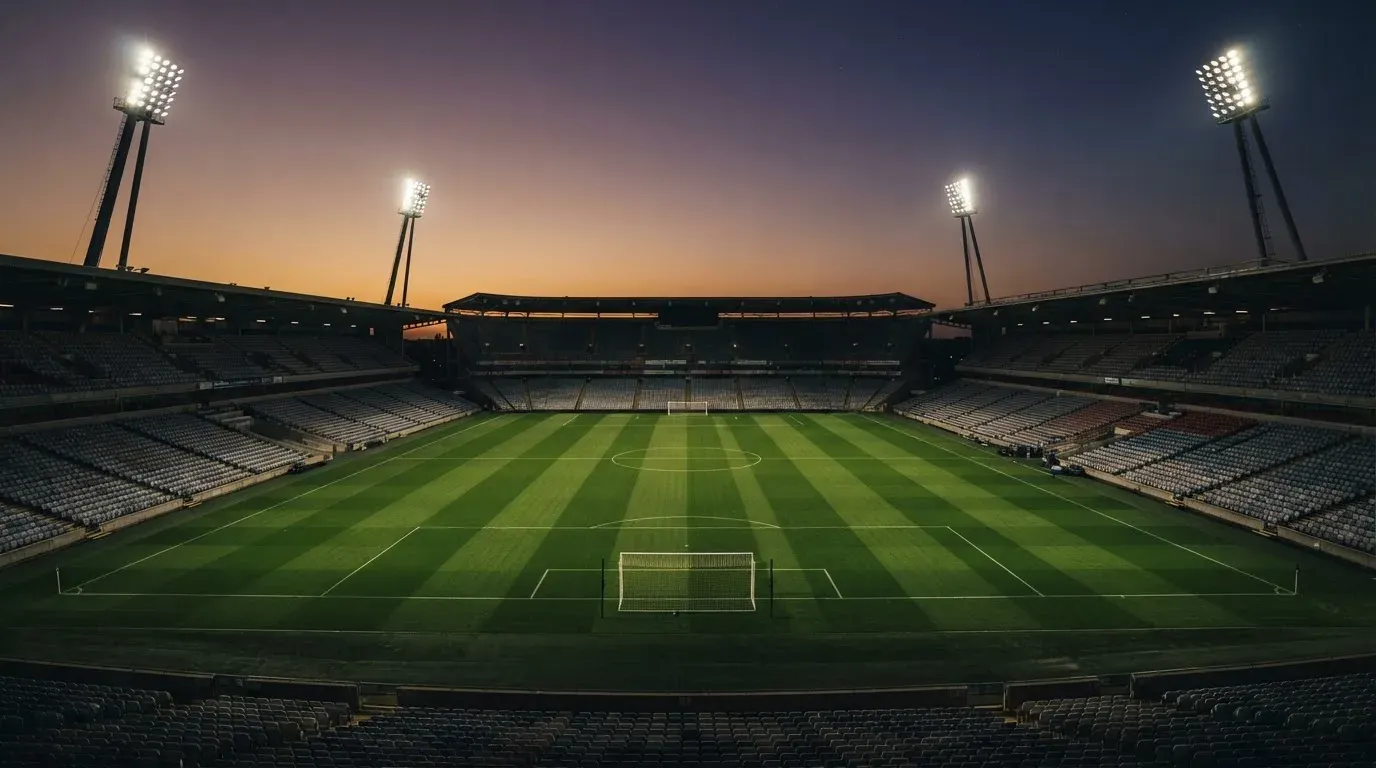 An empty football stadium with floodlight masts at dusk