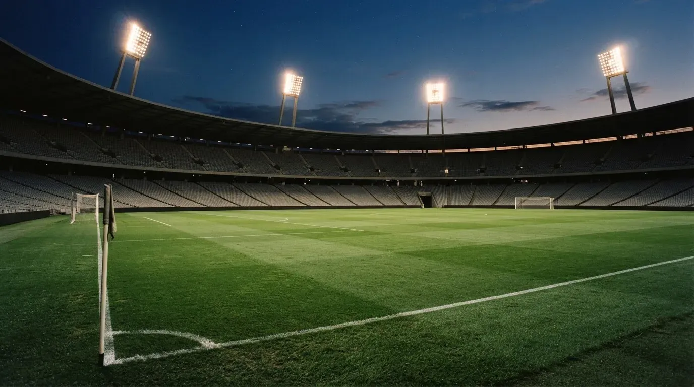 An empty football stadium with floodlight masts at dusk