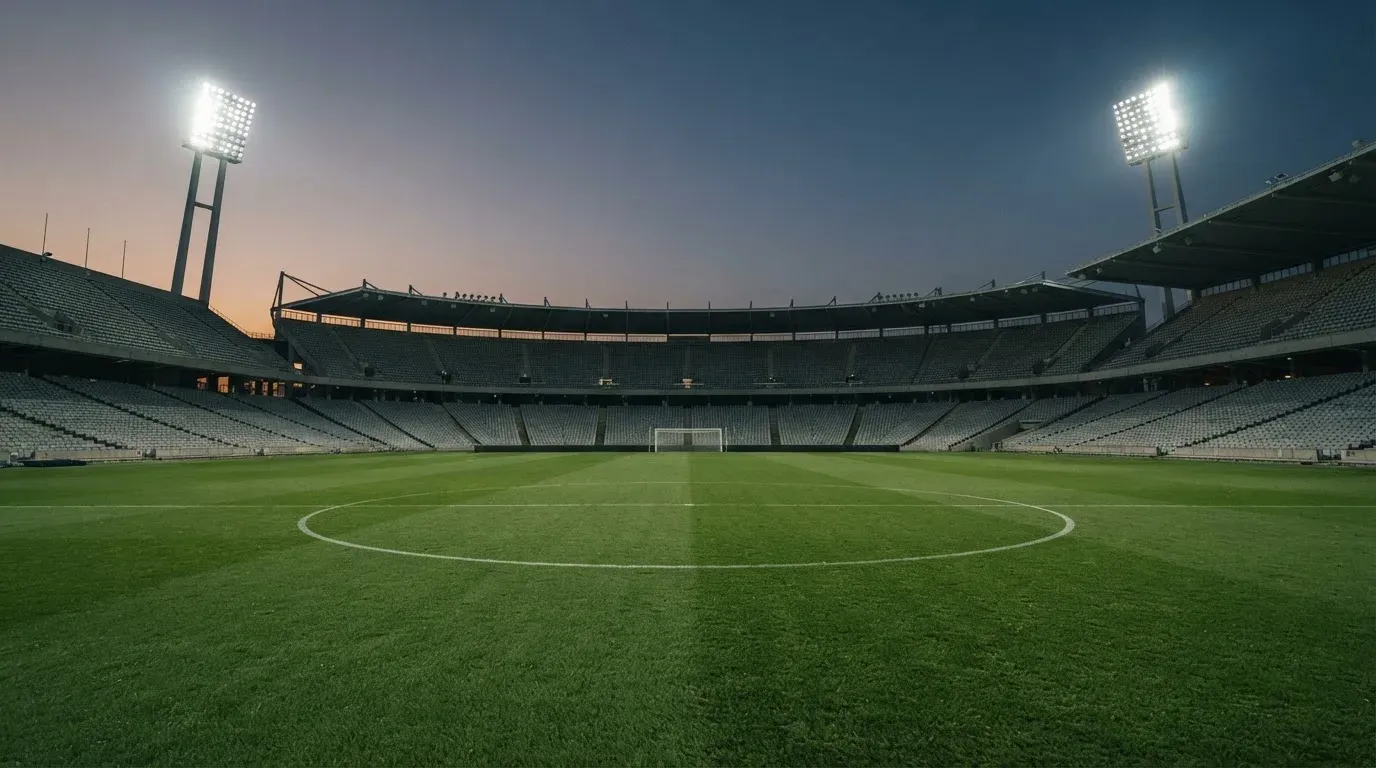 An empty football stadium with floodlight masts at dusk