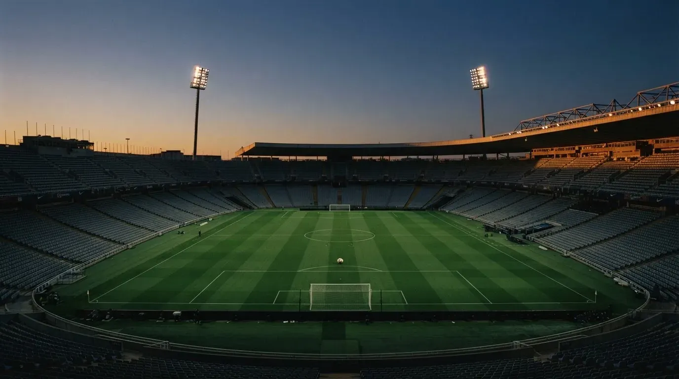 An empty football stadium with floodlight masts at dusk