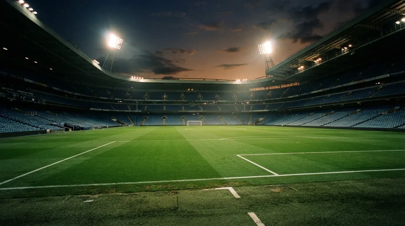 An empty football stadium with floodlight masts at dusk