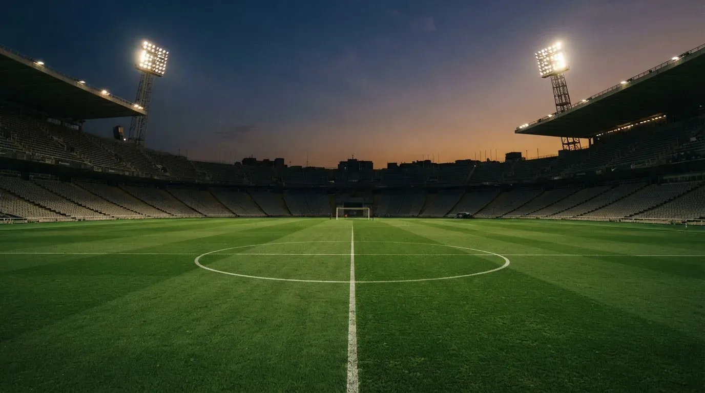 An empty football stadium with floodlight masts at dusk