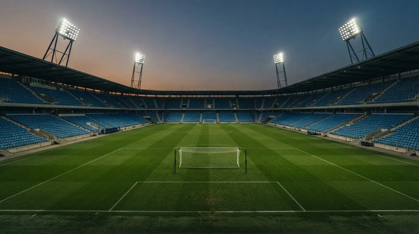 An empty football stadium with floodlight masts at dusk