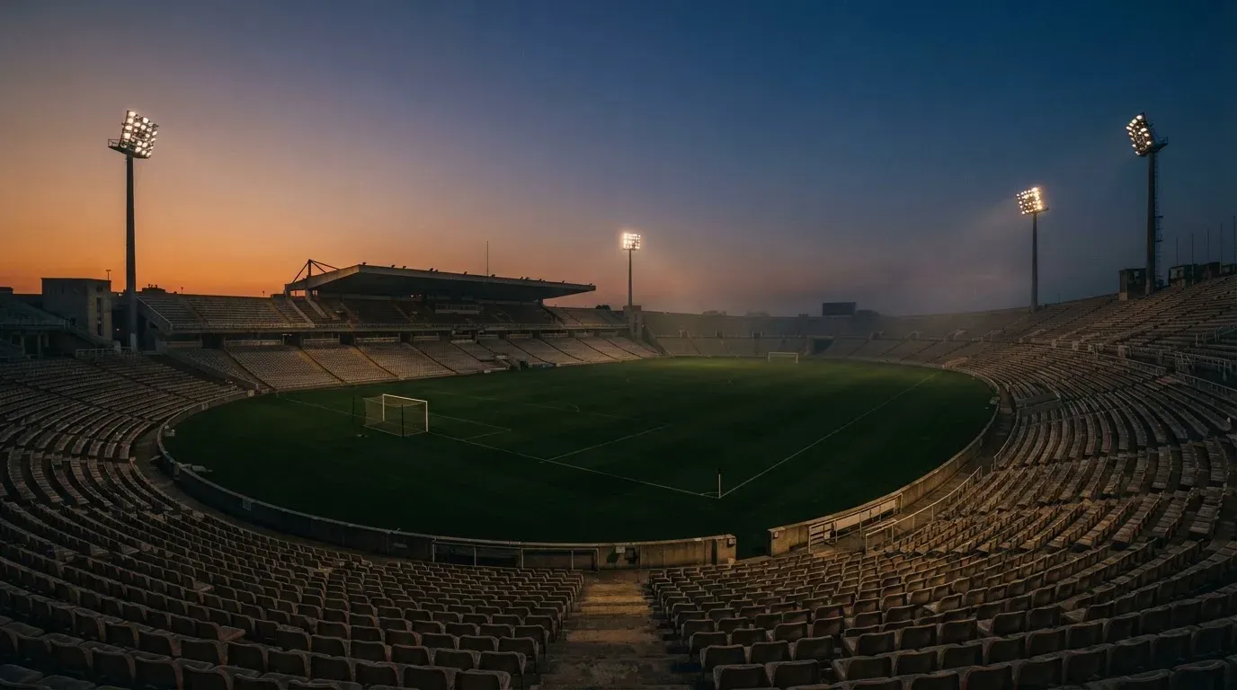 An empty football stadium with floodlight masts at dusk