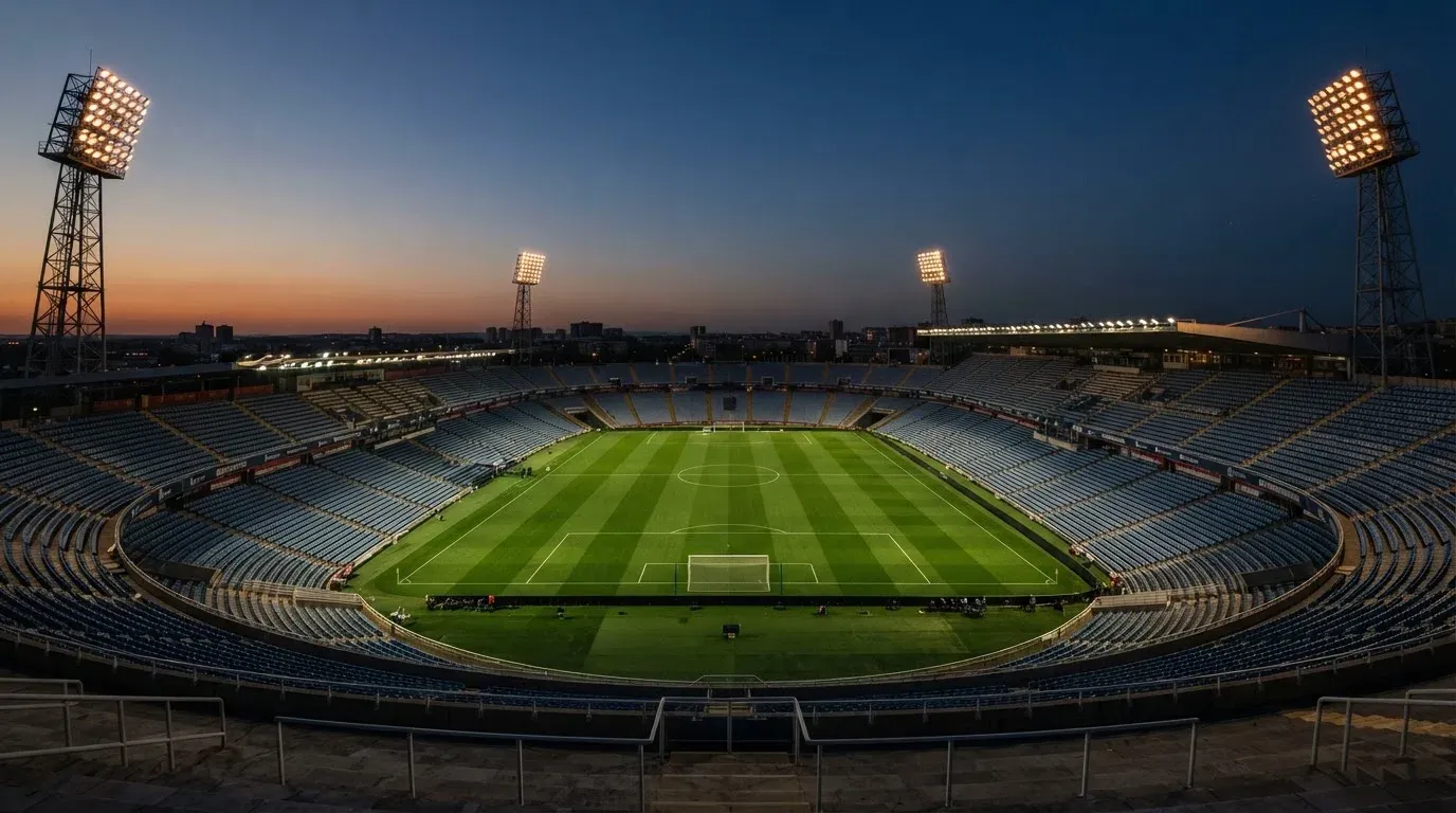 An empty football stadium with floodlight masts at dusk