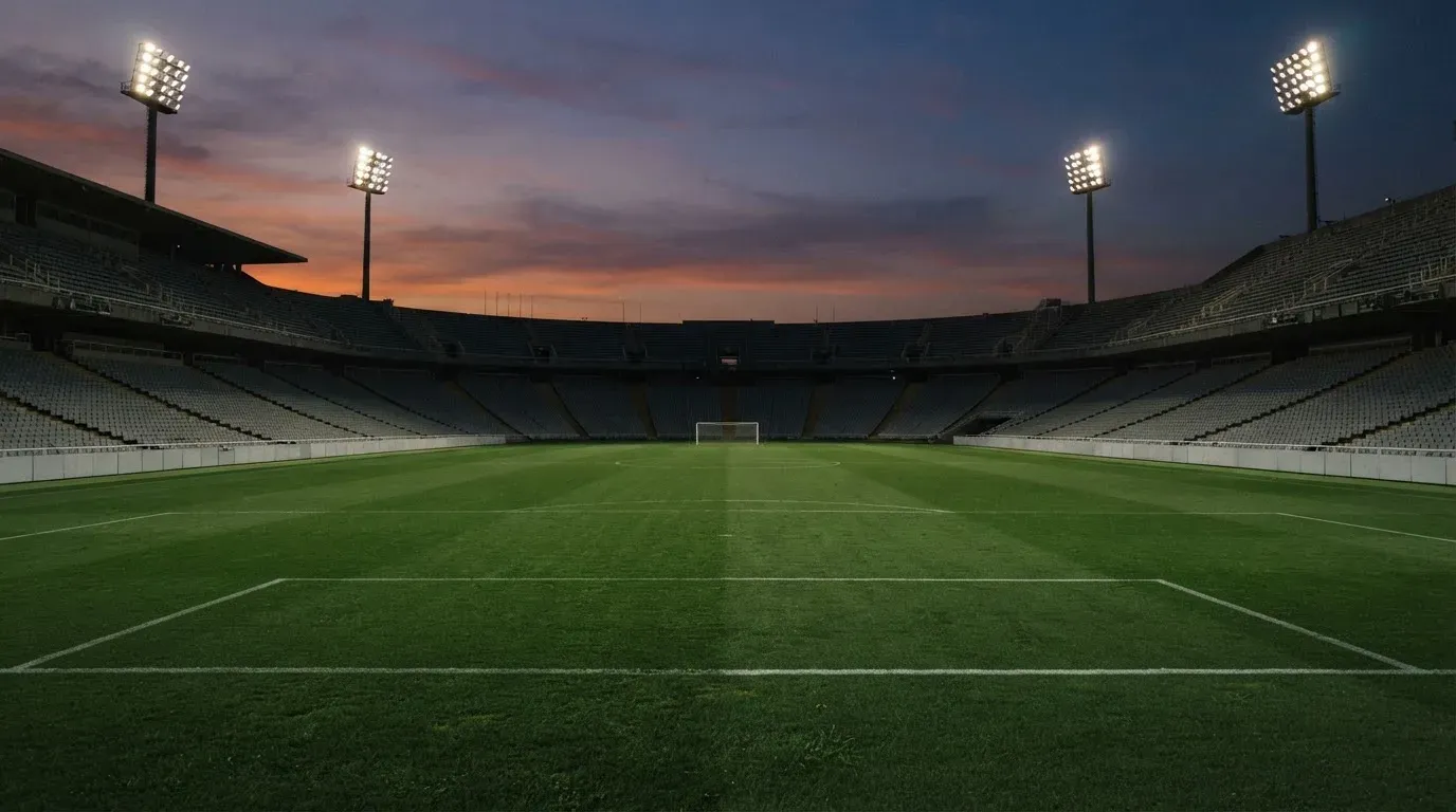 An empty football stadium with floodlight masts at dusk