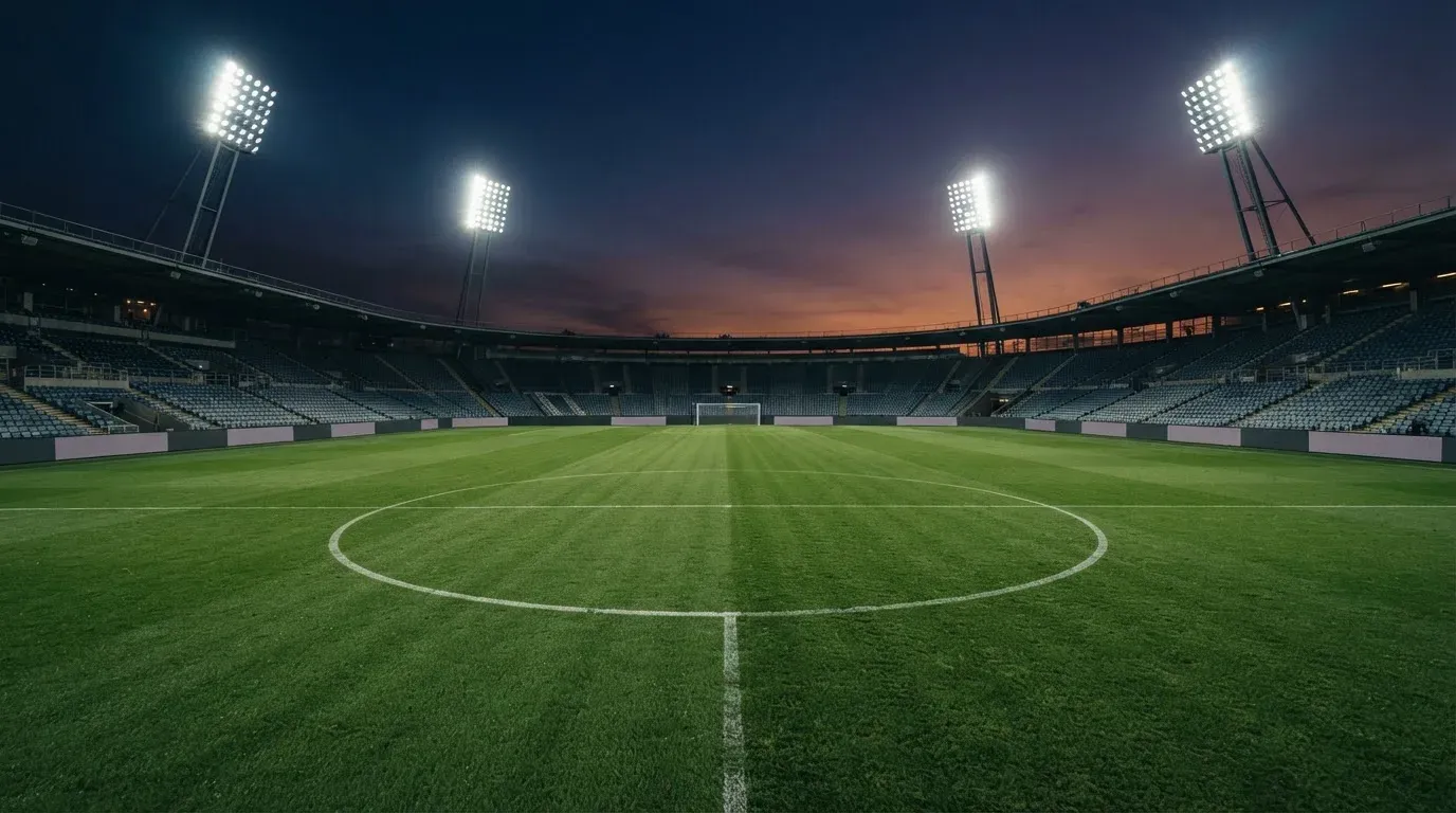 An empty football stadium with floodlight masts at dusk
