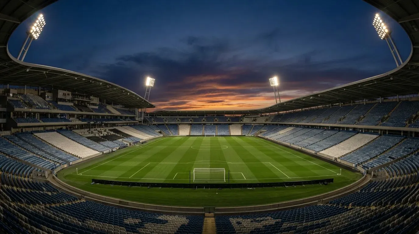 An empty football stadium with floodlight masts at dusk
