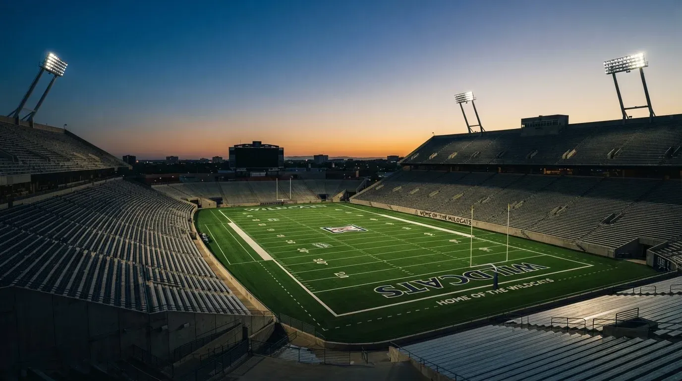 An empty football stadium with floodlight masts at dusk