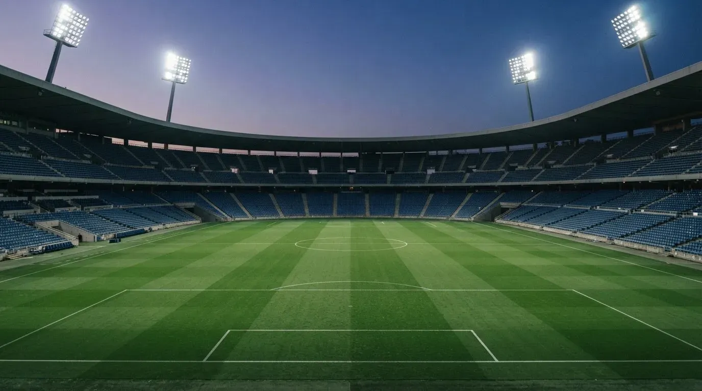 An empty football stadium with floodlight masts at dusk