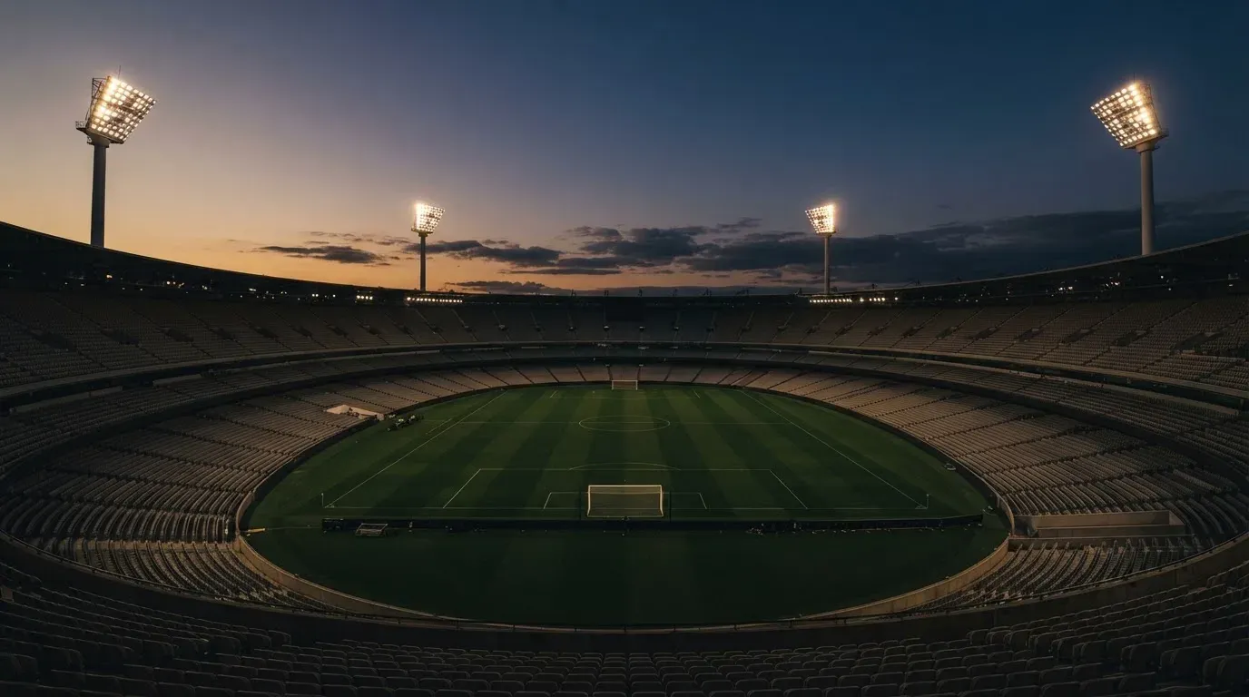 An empty football stadium with floodlight masts at dusk